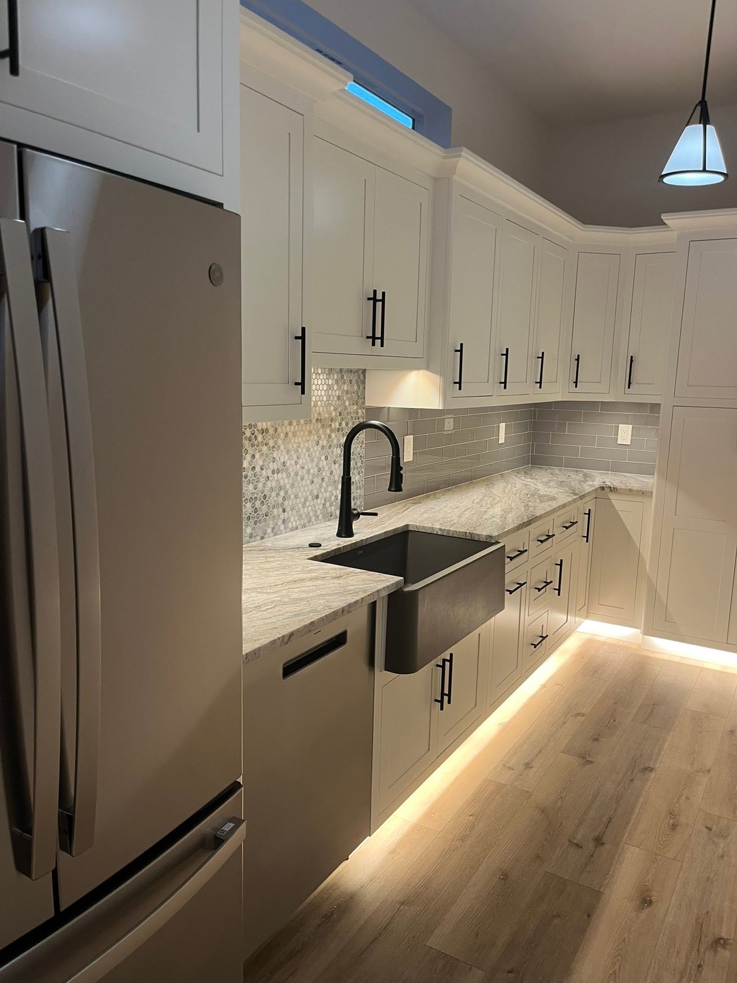 A kitchen with warm LED lighting glowing under the upper cabinets and along the floor edge.